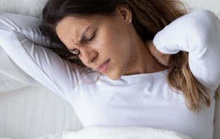 woman holding neck after poor night of sleeping